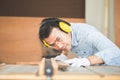 Carpenter working in wood workshop. Skilled woodworker wearing safety gear using circular saw to cut a wood on workbench Royalty Free Stock Photo