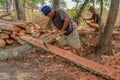 Carpenter works with hand tool a tree trunk. Worker on island of Bali sculpts a trough in a wooden beam. Heavy manual job