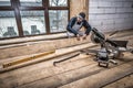 Carpenter works with wooden board. Mitre saw Royalty Free Stock Photo