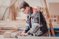 A carpenter works on woodworking the machine tool. Carpenter working on woodworking machines in carpentry shop. Royalty Free Stock Photo