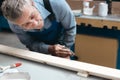Carpenter& x27;s work in the carpentry shop. An elderly male cabinetmaker carefully examines a wooden board.