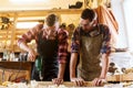 Carpenters with drill drilling plank at workshop