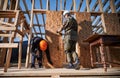 Carpenter hammering nail into OSB panel while building wooden frame house. Royalty Free Stock Photo