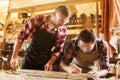 Carpenters with ruler and wood plank at workshop