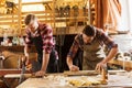 Carpenters working with saw and wood at workshop