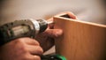 Carpentry industry - worker drills screws into the piece of plywood