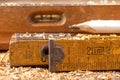 Carpentry measure, spirit level and pencil in sawdust on wooden table. Small carpentry work in a home workshop