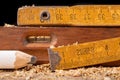 Carpentry measure, spirit level and pencil in sawdust on wooden table. Small carpentry work in a home workshop