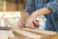 Carpentry professional, hand of asian young man, male carpenter use tape measure, tool on board wood in small shop. Woodwork,