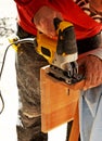 Carpenter cutting with a jig saw the beech wood stair step of a staircase