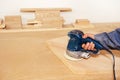 Carpentry work. The process of sanding a board with a power tool in a small workshop. Close-up Royalty Free Stock Photo