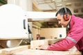 Carpentry worker cutting wood cross beam