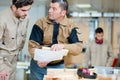 Carpentry workers talking holding plank industrial wood