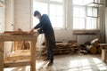 Carpentry workshop. Man using electric hand saw on wooden planks Royalty Free Stock Photo