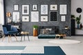 Carpet in grey spacious flat interior with blue armchair next to table near green futon. Real photo Royalty Free Stock Photo