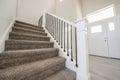Carpeted staircase with white newel post inside a house with white siding