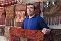 Carpet vendor showing his handmade products in his shop in Bukhara, Uzbekistan