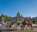 Carriage Ride In Victoria BC Canada. A horse drawn carriage with tourists passes the parliament building in Victoria