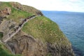 Tourists walking on Carrick-a-Rede Rope Bridge - Island in blue ocean - Northern Ireland tourism
