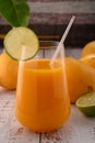 Carrot beverage macro with lime on white vintage wooden desktop with mangos Royalty Free Stock Photo