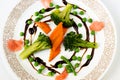 Carrot,broccoli,peas and ginger in balsamico circle on white plate.