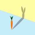 Carrot with bunny shape shadow on pastel blue and yellow background. Minimal easter concept