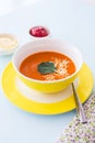 Carrot cheese soup with parsley in yellow bowl, blue background Royalty Free Stock Photo