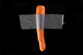 Carrot fixed with big gray scotch tape on a black background