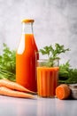 Carrot juice in a glass and bottle and fresh carrots with leaves