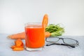 Carrot juice in a glass cup, glasses for vision on a light gray concrete background. Concept carrot for good eyesight Royalty Free Stock Photo
