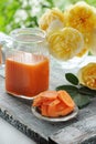 Carrot juice in a jar of transparent glass on a background of yellow roses. Royalty Free Stock Photo