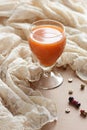 Carrot orange juice in a vintage glass on vintage gauzy textile