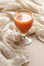 Carrot orange juice in a vintage glass on vintage gauzy textile