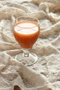 Carrot orange juice in a vintage glass on vintage gauzy textile