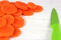 Carrot slices with knife on rutic white chopping board