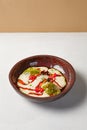 Carrot soup with creamy espuma in dark ceramic bowl. Vegetable cream soup in modern dishware with hard shadow