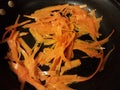 Carrot strips in oil cooking in frying pan