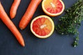 Carrots, blood orange and thyme herbs on dark board, top view