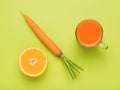 Carrots, half an orange and a glass of smoothies on a green background. Flat lay