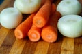 Carrots and onion cleaned but not cut on a cutting board on a wooden background, fresh vegetables for cooking, natural from the ga Royalty Free Stock Photo