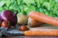 Carrots, red union and tomatoes, against green background Royalty Free Stock Photo