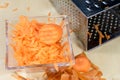 Carrots take off on a kitchen grater. Kitchen countertop and preparation of salads.