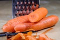 Carrots take off on a kitchen grater. Kitchen countertop and preparation of salads.