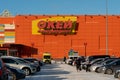 Cars and an ambulance stand in front of the entrance to the OKay supermarket with the name in Russian on the facade on a sunny