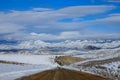 Cars in the distance drive along the dirt road crossing the snowy countryside Royalty Free Stock Photo