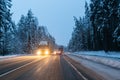Cars drive with headlights on the winter road in a snow storm in the twilight when snow is flying. Concept of driving in Royalty Free Stock Photo