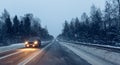 Cars drive  with headlights on the winter road in a snow storm in the  twilight  when snow is flying. Concept of driving in the Royalty Free Stock Photo