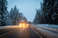 Cars drive with headlights on the winter road in a snow storm in the twilight when snow is flying. Concept of driving in