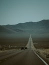 Cars driving down a deserted highway against mountains in the United States