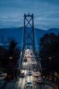 cars driving down a street in front of a tall metal bridge